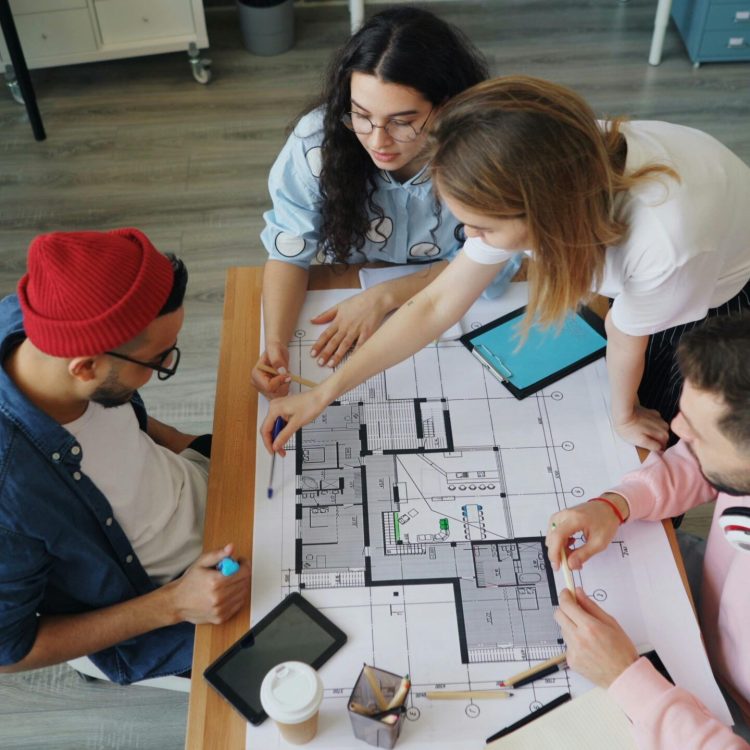 Young creative professionals discussing an architectural blueprint in a modern office setting.